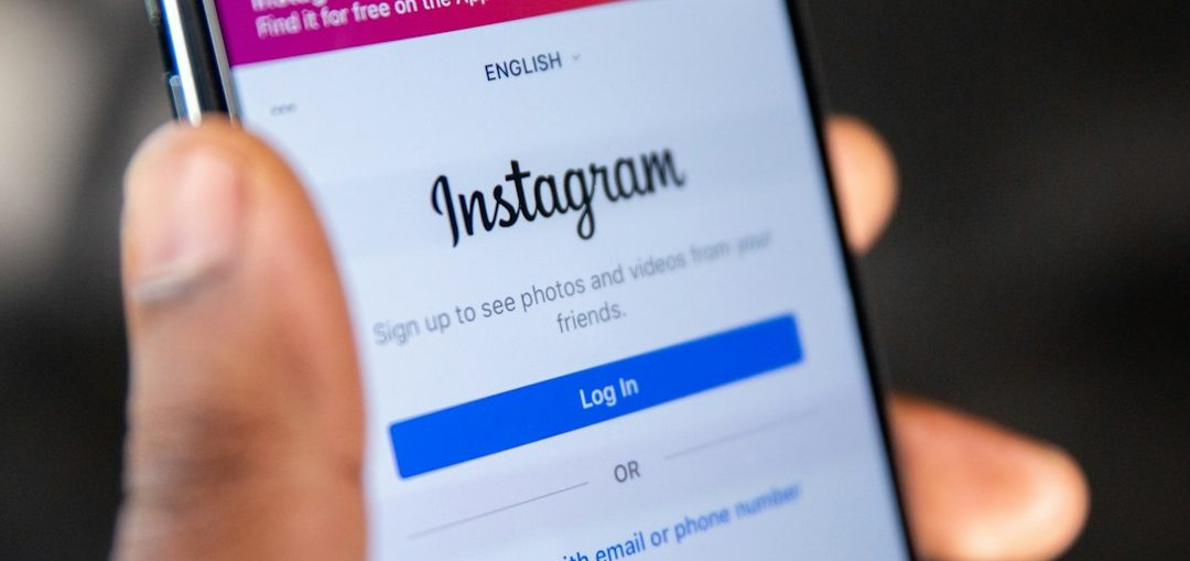 Wie schreibe ich eine perfekte Caption? Ganz sicher nicht mit KI, besser mit menschlichem Text Generator. Hand hält ein Smartphone mit der Instagram-App geöffnet.