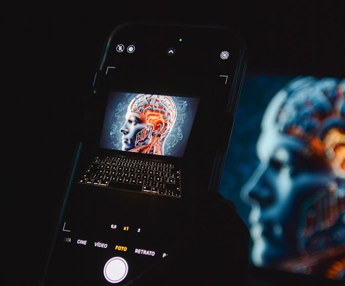 Smartphone zeigt digitalisierte Gehirnansicht nebeneinander mit einer Laptop-Tastatur.
