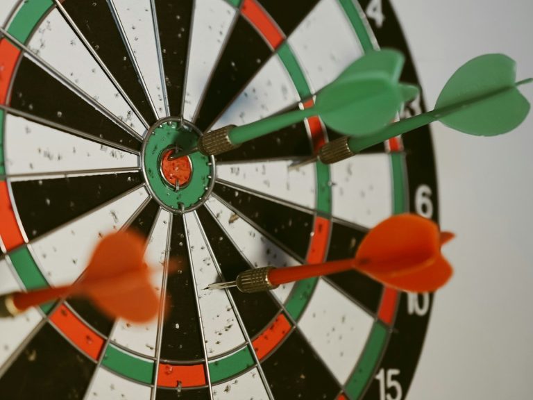 Mit Kreativität Texte erstellen lassen: Volltreffer für Ihre Webseite Darts stecken in einem Ziel mit schwarzen und grünen Segmenten. Ich treffe mit meinen Texten ins Ziel!
