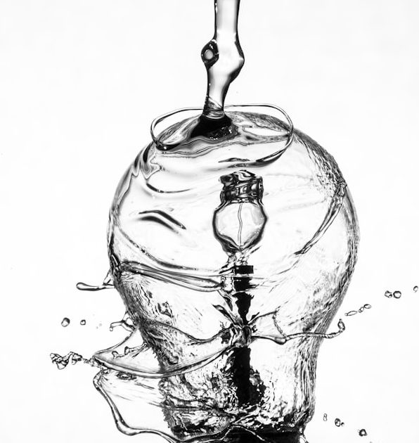 Wassertropfen fallen auf eine Glühbirne, die in klarem Wasser steht.